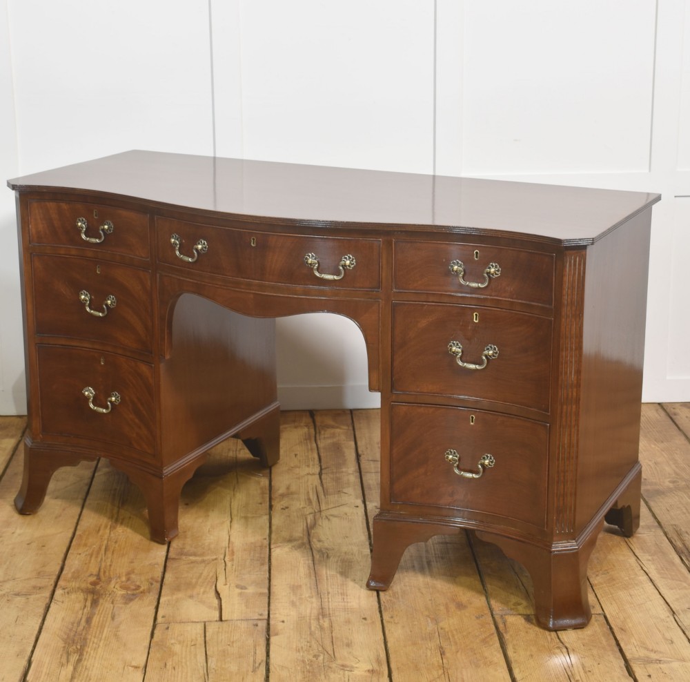 A mahogany serpentine-fronted dressing table featuring nine drawers with brass swan-neck handles and a shaped central kneehole. View VIII