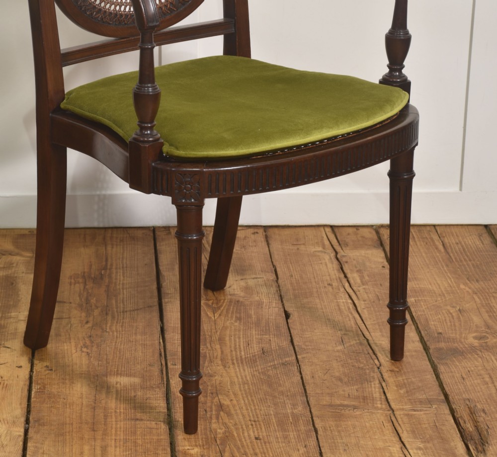 Sheraton Revival mahogany armchair featuring an oval cane back panel with carved central medallion, olive green velvet seat cushion, and turned fluted front legs. View IV