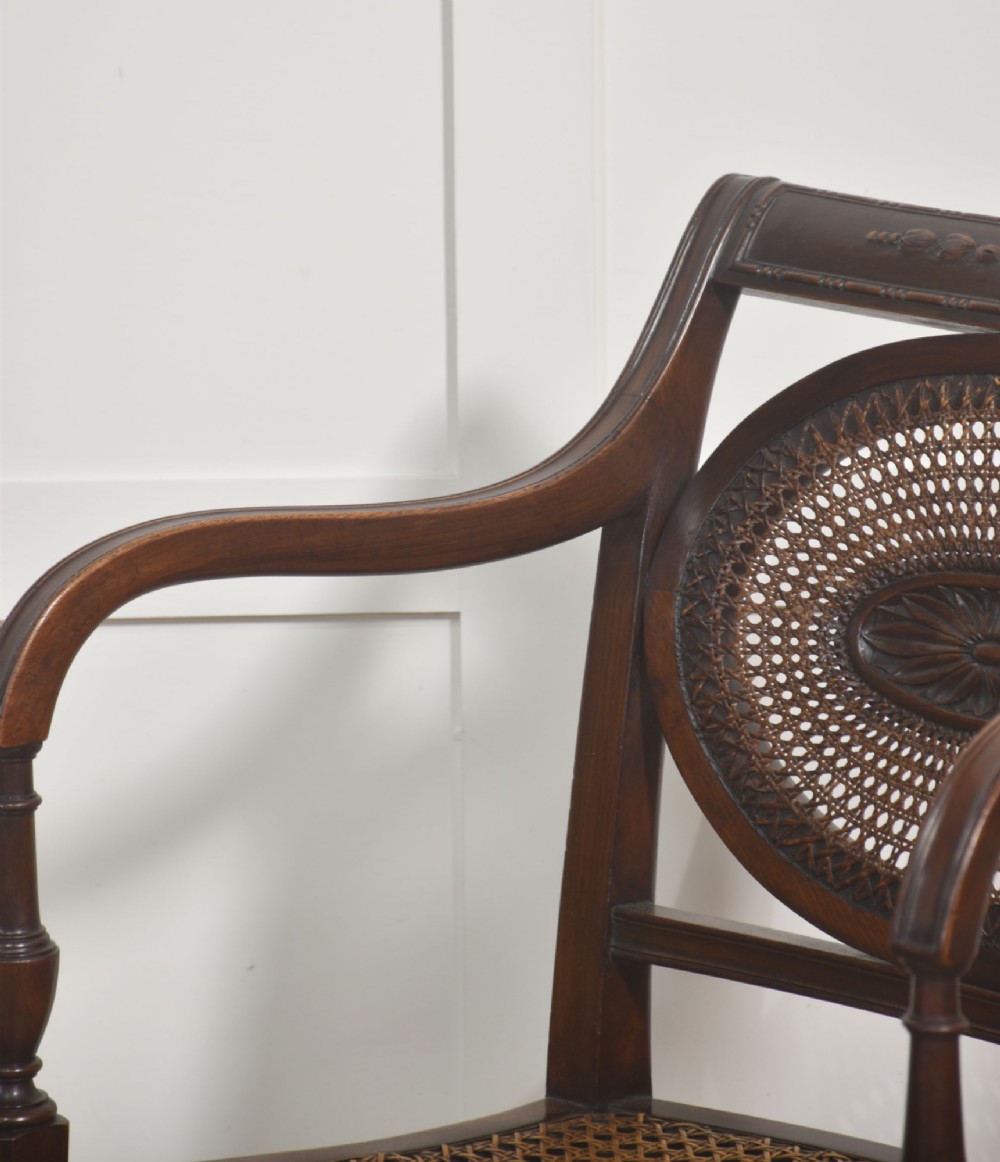 Sheraton Revival mahogany armchair featuring an oval cane back panel with carved central medallion, olive green velvet seat cushion, and turned fluted front legs. View VII