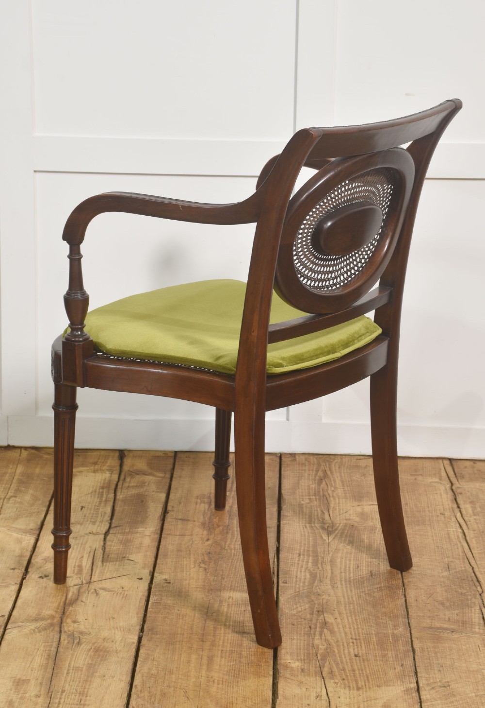 Sheraton Revival mahogany armchair featuring an oval cane back panel with carved central medallion, olive green velvet seat cushion, and turned fluted front legs. View IX