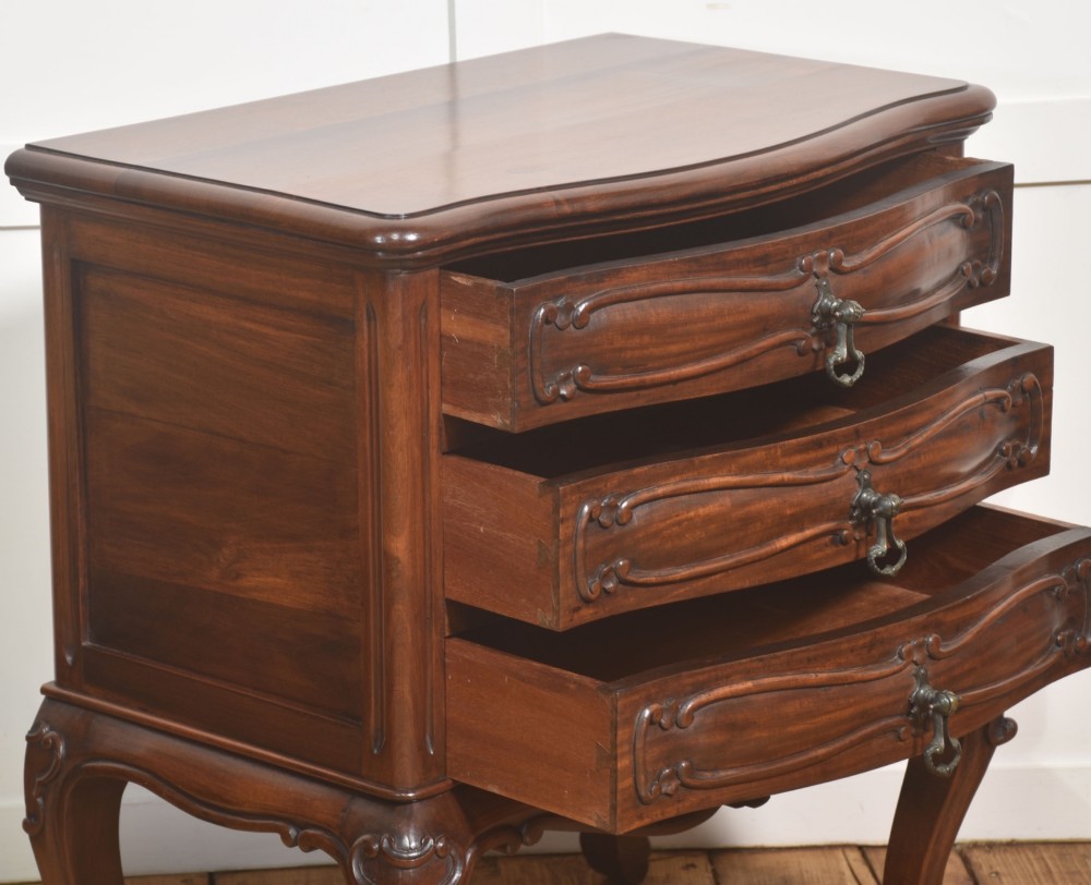 A French Louis XV style walnut chest featuring three carved drawers elevated on cabriole legs with brass drop handles. View IV