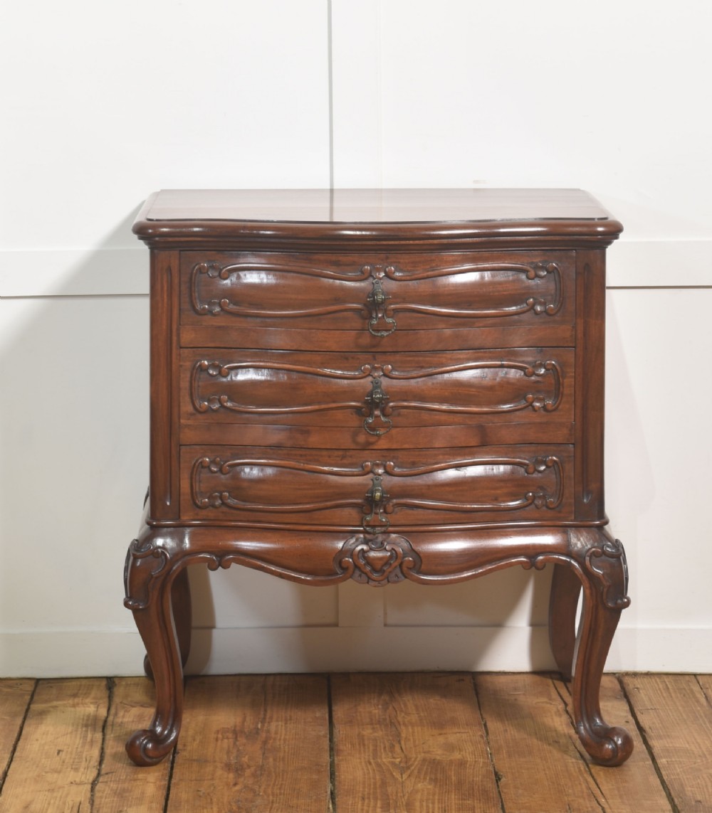 A French Louis XV style walnut chest featuring three carved drawers elevated on cabriole legs with brass drop handles.