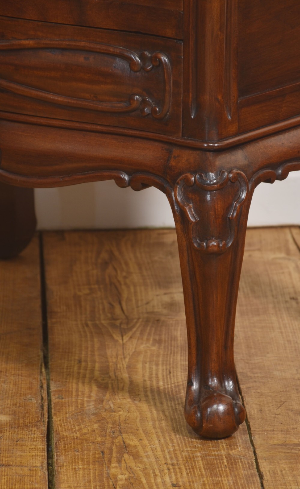 A French Louis XV style walnut chest featuring three carved drawers elevated on cabriole legs with brass drop handles. View VIII