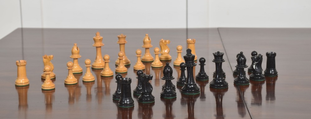 A late 19th-century Staunton chess set featuring natural light boxwood and ebonised black carved wooden pieces arrayed on a polished tabletop. View IV