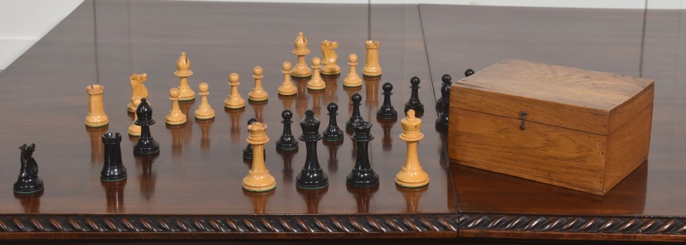 A late 19th-century Staunton chess set featuring natural light boxwood and ebonised black carved wooden pieces arrayed on a polished tabletop. View VIII