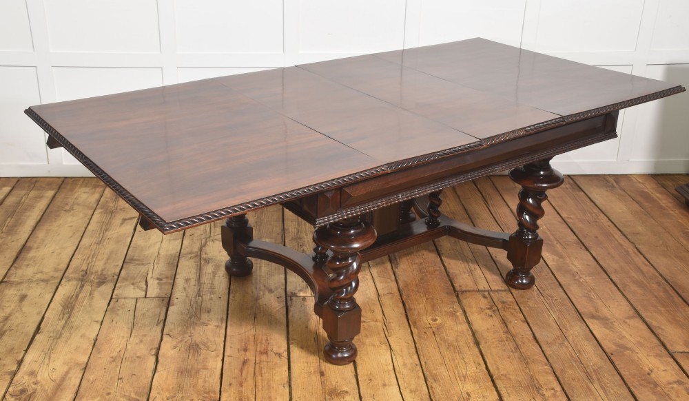 A large 19th-century Portuguese rosewood extending dining table with carved barley-twist legs, an H-stretcher base, and two removable extension leaves standing behind it. View V