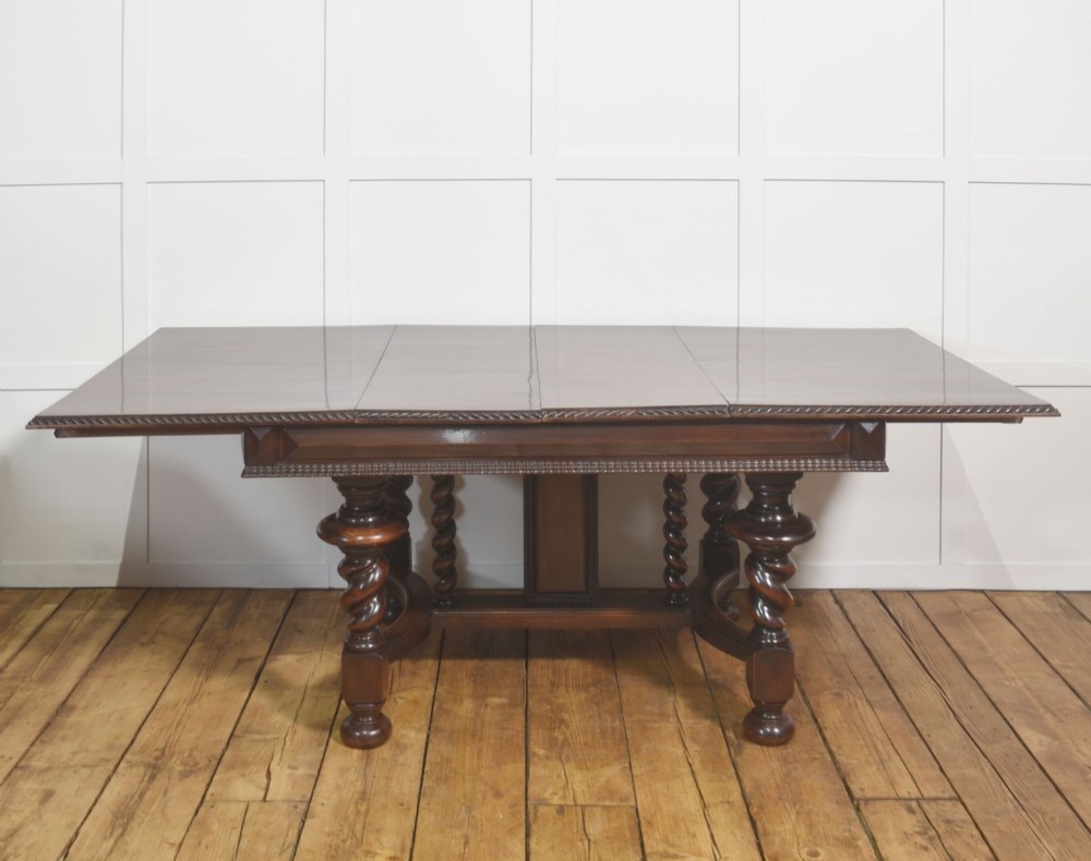 A large 19th-century Portuguese rosewood extending dining table with carved barley-twist legs, an H-stretcher base, and two removable extension leaves standing behind it. View IX