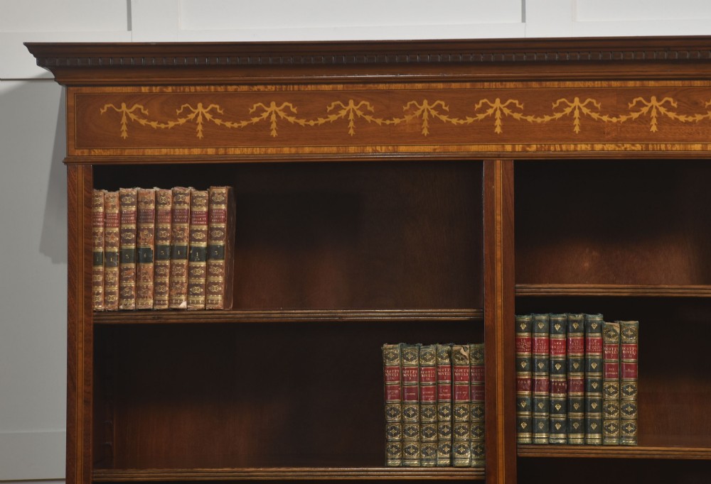 A tall, double-bay mahogany open bookcase featuring delicate satinwood festoon inlays along the top frieze and multiple fixed shelves containing books. View IV