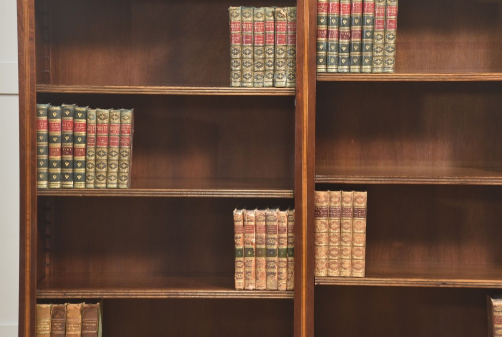 A tall, double-bay mahogany open bookcase featuring delicate satinwood festoon inlays along the top frieze and multiple fixed shelves containing books. View V