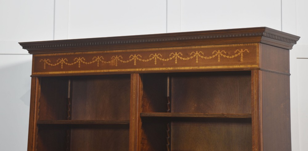 A tall, double-bay mahogany open bookcase featuring delicate satinwood festoon inlays along the top frieze and multiple fixed shelves containing books. View XII