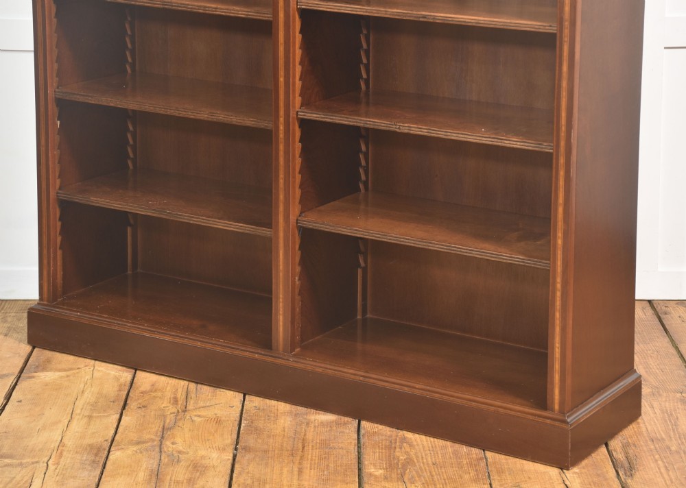 A tall, double-bay mahogany open bookcase featuring delicate satinwood festoon inlays along the top frieze and multiple fixed shelves containing books. View XIII