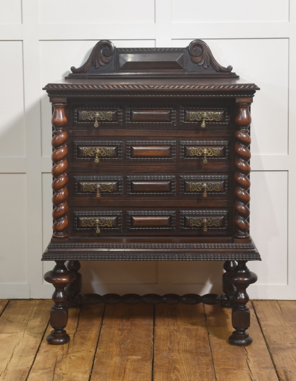 A 19th-century dark rosewood chest on stand with four drawers, pierced brass drop handles, barley twist side columns, and turned legs.
