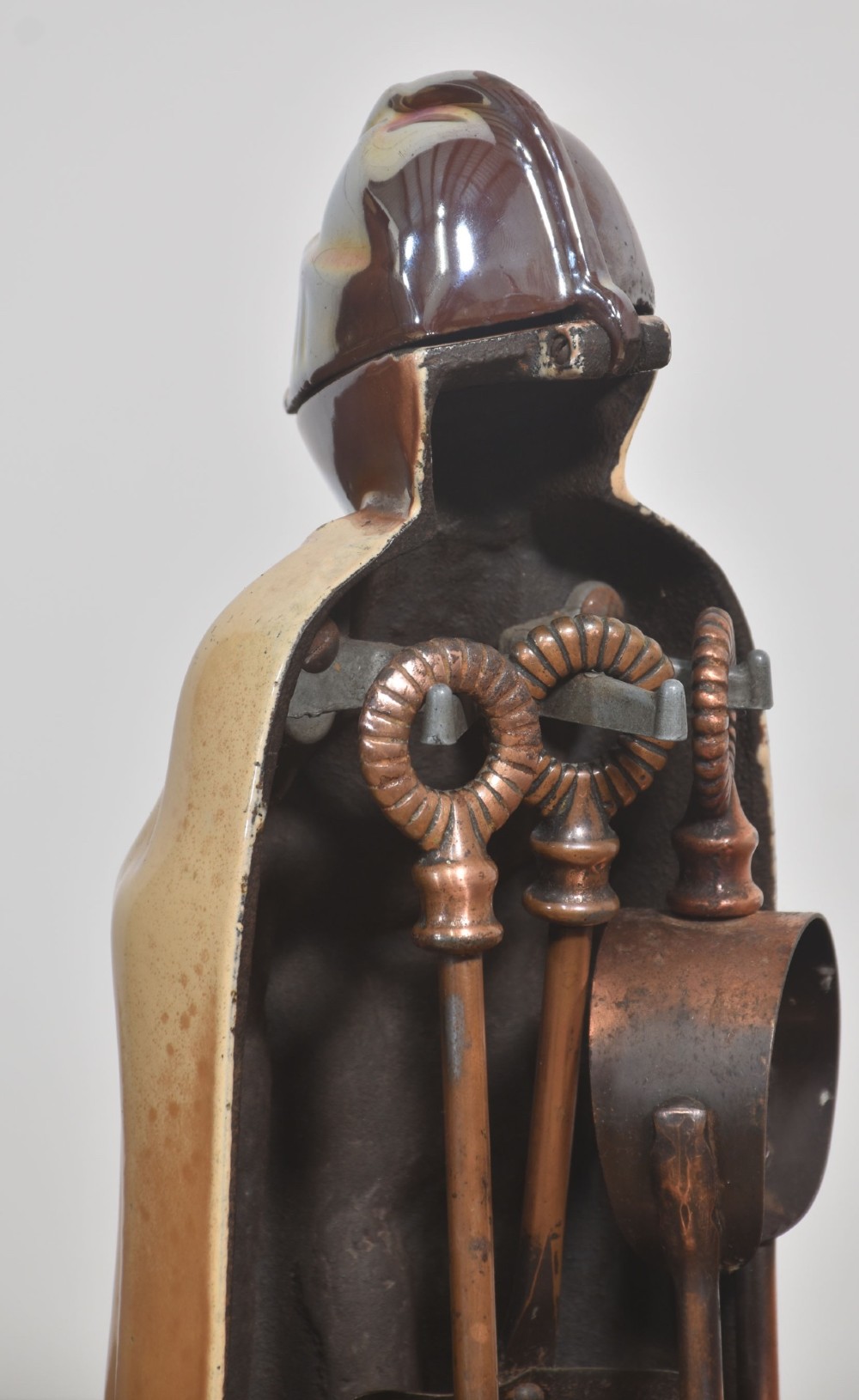 A metallic knight in full armour fireside companion stand holding a shovel and tongs, with a matching brush resting beside it. View V
