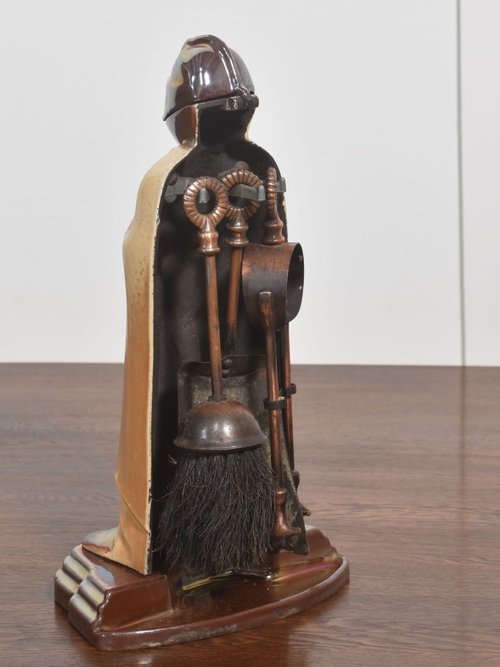 A metallic knight in full armour fireside companion stand holding a shovel and tongs, with a matching brush resting beside it. View VI