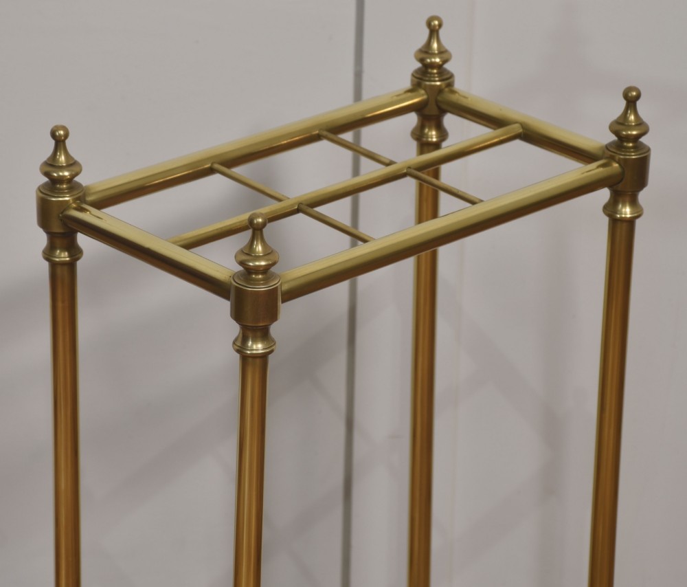 A 19th-century rectangular umbrella stand featuring brass upright posts, brass top rail dividers with corner finials, and a dark cast iron drip tray base. View III