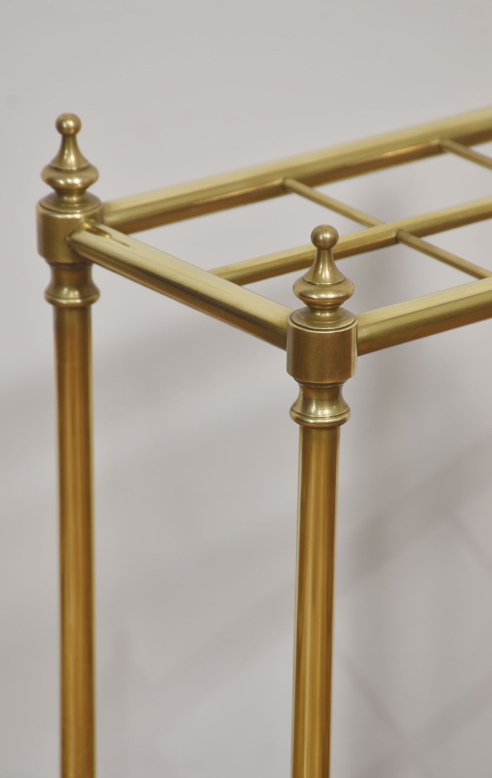 A 19th-century rectangular umbrella stand featuring brass upright posts, brass top rail dividers with corner finials, and a dark cast iron drip tray base. View IV