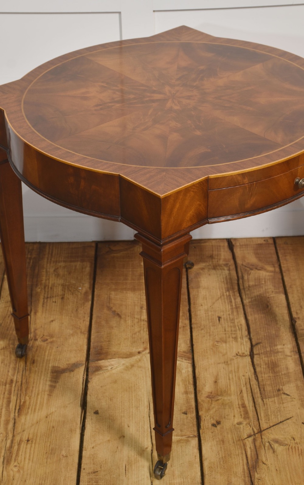 A pair of mahogany Sheraton Revival side tables featuring shaped inlaid tops, single frieze drawers, fluted tapered legs, and brass castors. View III