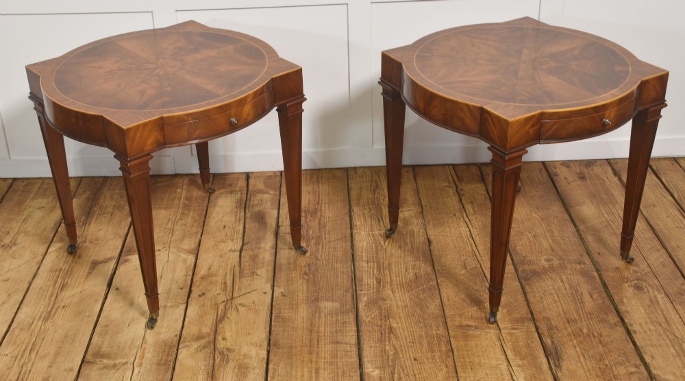 A pair of mahogany Sheraton Revival side tables featuring shaped inlaid tops, single frieze drawers, fluted tapered legs, and brass castors. View V
