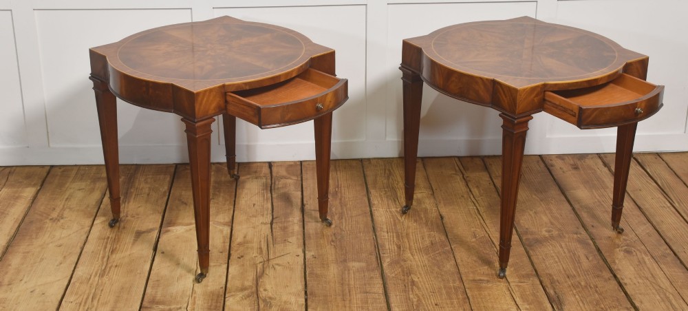 A pair of mahogany Sheraton Revival side tables featuring shaped inlaid tops, single frieze drawers, fluted tapered legs, and brass castors. View VI