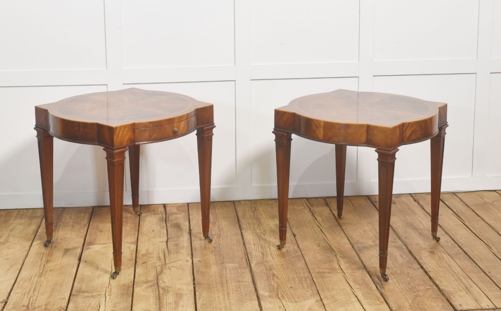 A pair of mahogany Sheraton Revival side tables featuring shaped inlaid tops, single frieze drawers, fluted tapered legs, and brass castors. View VII