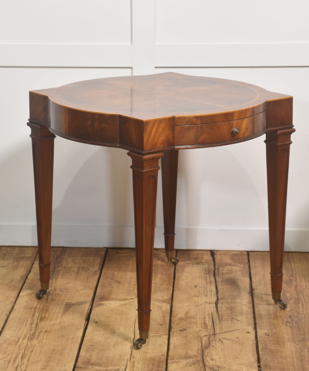 A pair of mahogany Sheraton Revival side tables featuring shaped inlaid tops, single frieze drawers, fluted tapered legs, and brass castors. View VIII
