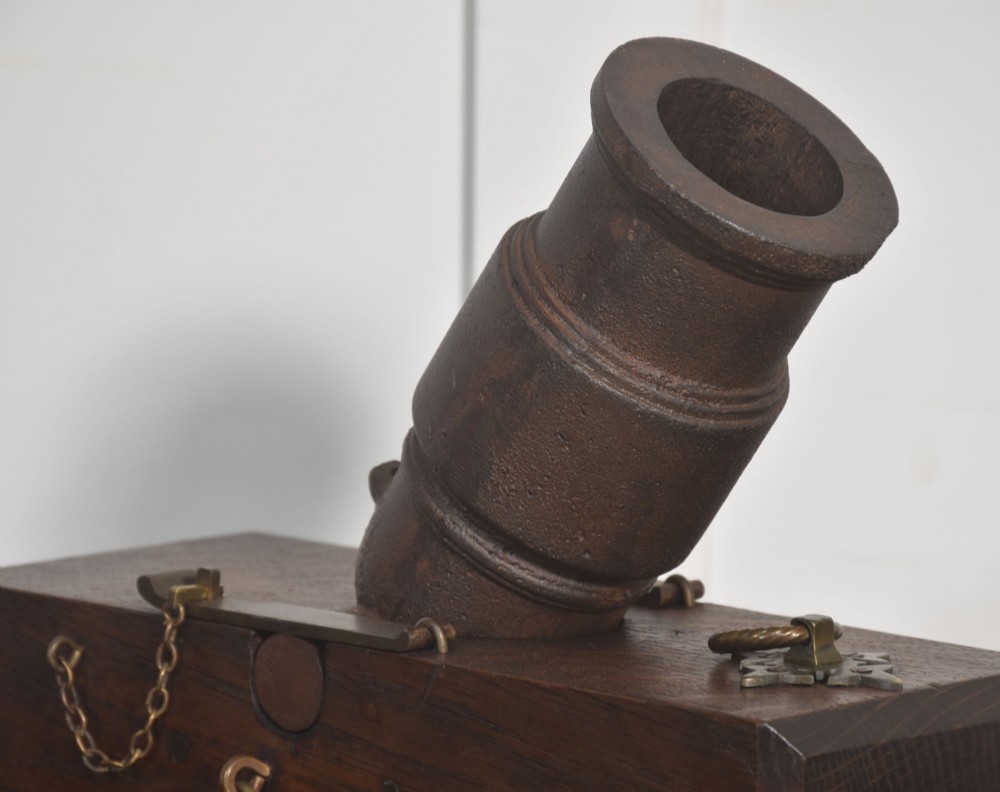 A 19th-century cast-iron signal mortar mounted at an angle on a dark oak carriage with brass side handles and chains. View III