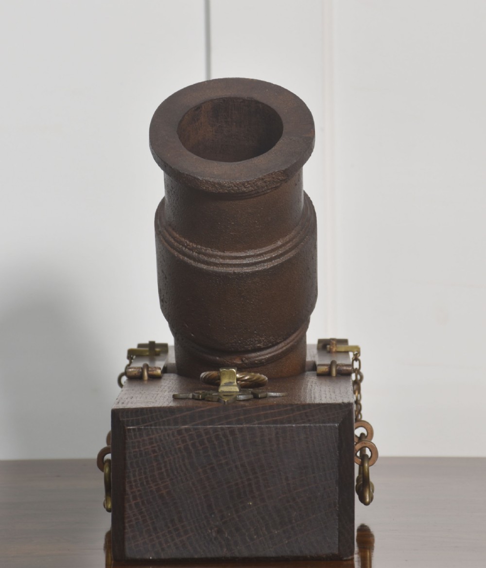 A 19th-century cast-iron signal mortar mounted at an angle on a dark oak carriage with brass side handles and chains. View IV
