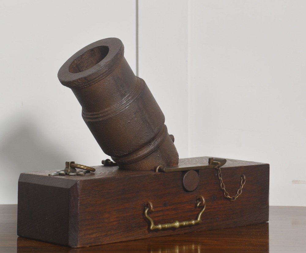 A 19th-century cast-iron signal mortar mounted at an angle on a dark oak carriage with brass side handles and chains. View V