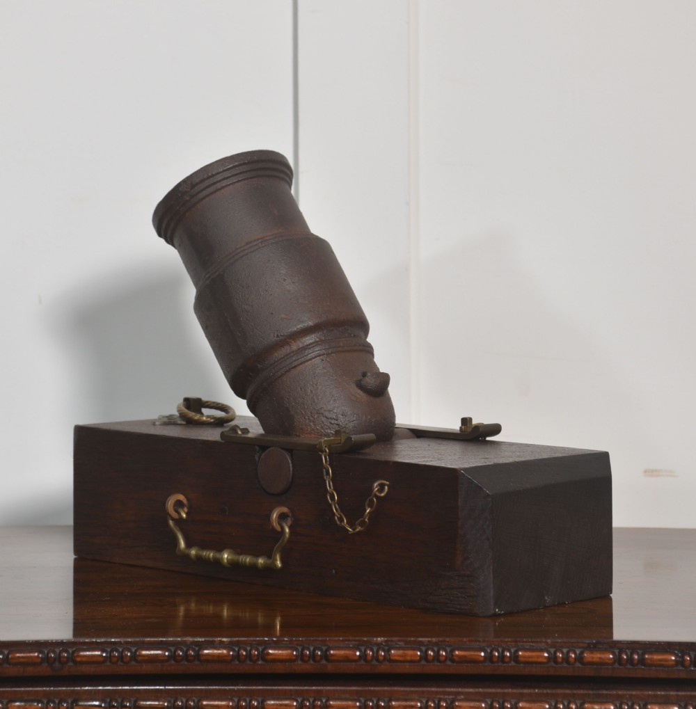 A 19th-century cast-iron signal mortar mounted at an angle on a dark oak carriage with brass side handles and chains. View VI