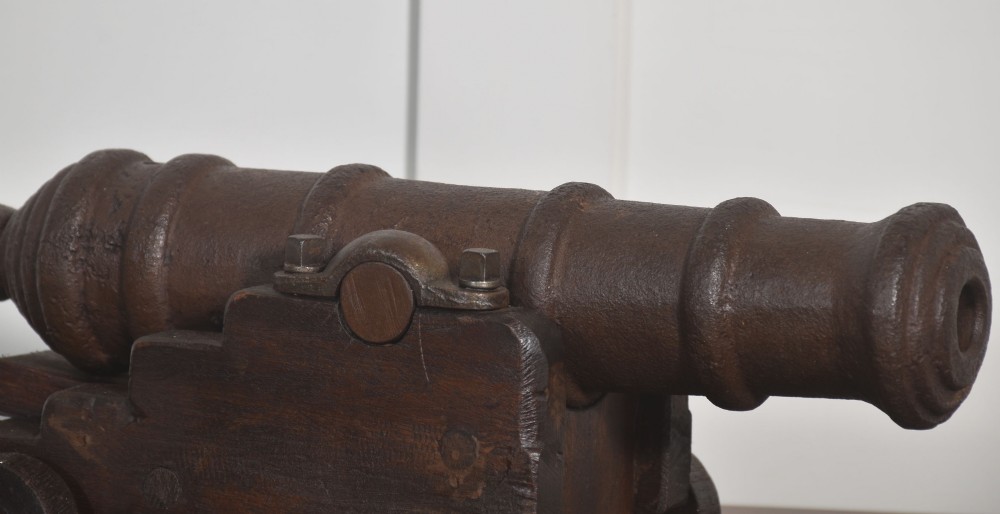 A nineteenth-century cast-iron signal cannon with a dark patina, mounted on a stepped dark oak carriage with wooden wheels. View IV