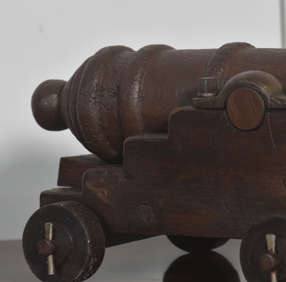 A nineteenth-century cast-iron signal cannon with a dark patina, mounted on a stepped dark oak carriage with wooden wheels. View V