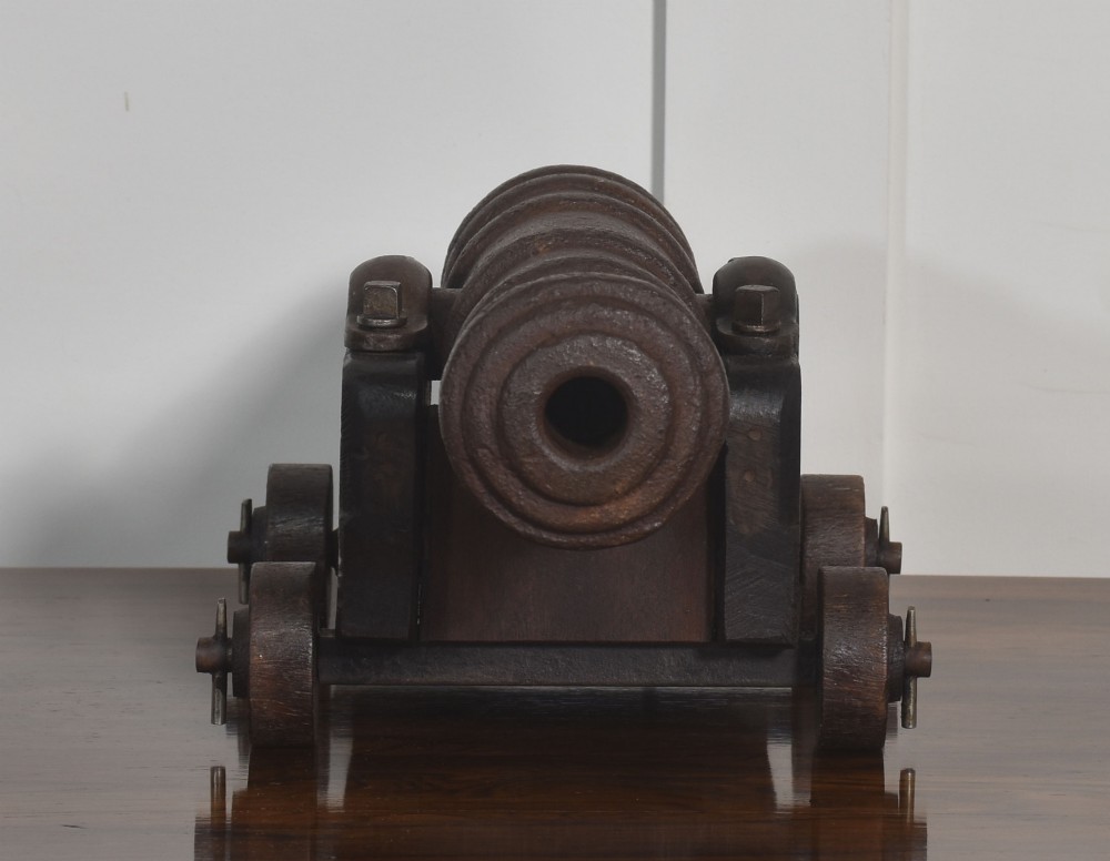 A nineteenth-century cast-iron signal cannon with a dark patina, mounted on a stepped dark oak carriage with wooden wheels. View VI