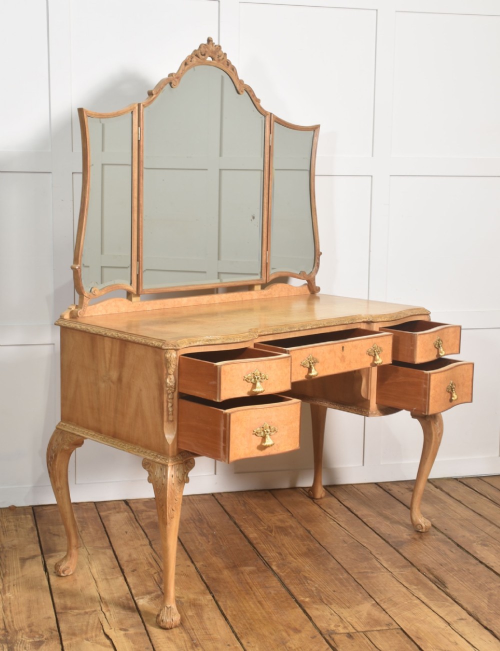 A light burr walnut dressing table featuring five drawers, brass handles, carved cabriole legs, a three-piece folding mirror, and a matching upholstered stool. View X