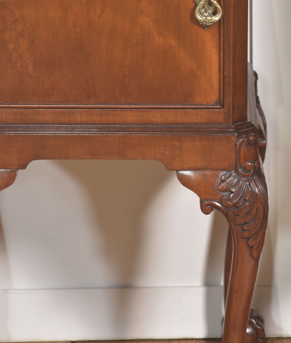 A pair of warm brown mahogany Chippendale style bedside cabinets featuring carved cabriole legs ending in ball and claw feet, flame mahogany single door cupboards, brass drop handles, and pull-out brush slides. View V
