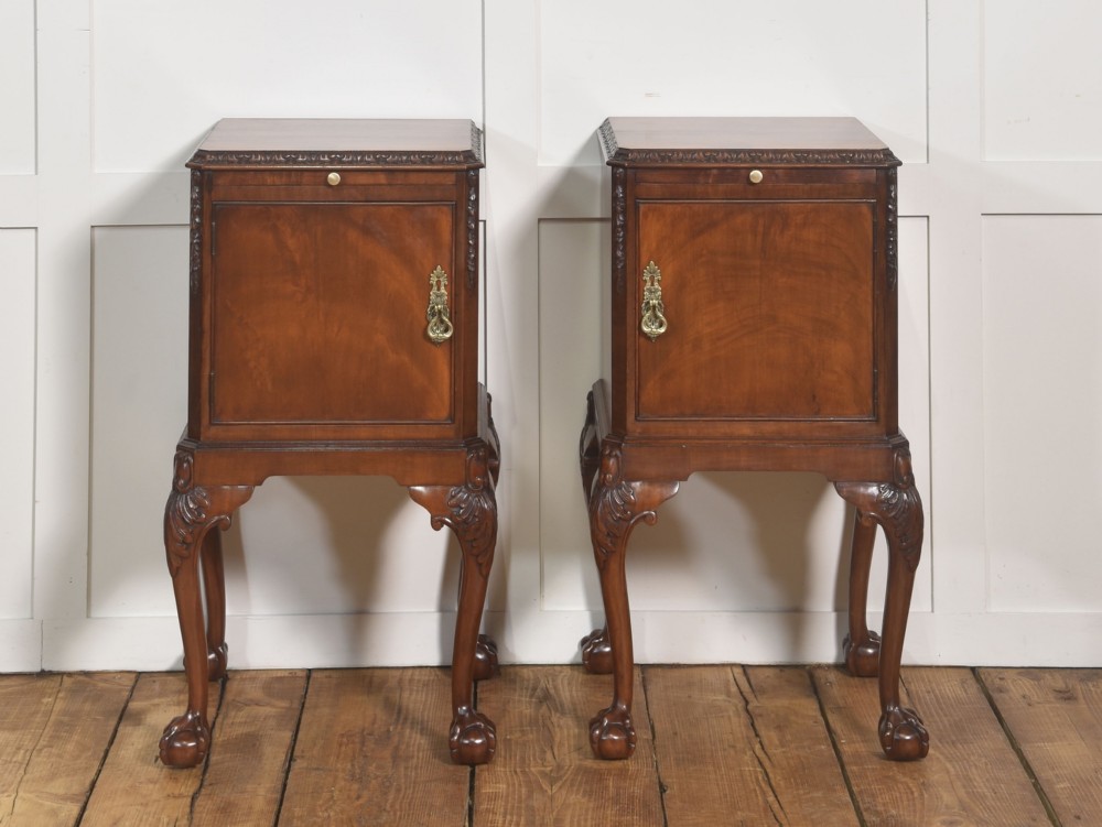 A pair of warm brown mahogany Chippendale style bedside cabinets featuring carved cabriole legs ending in ball and claw feet, flame mahogany single door cupboards, brass drop handles, and pull-out brush slides. View VI