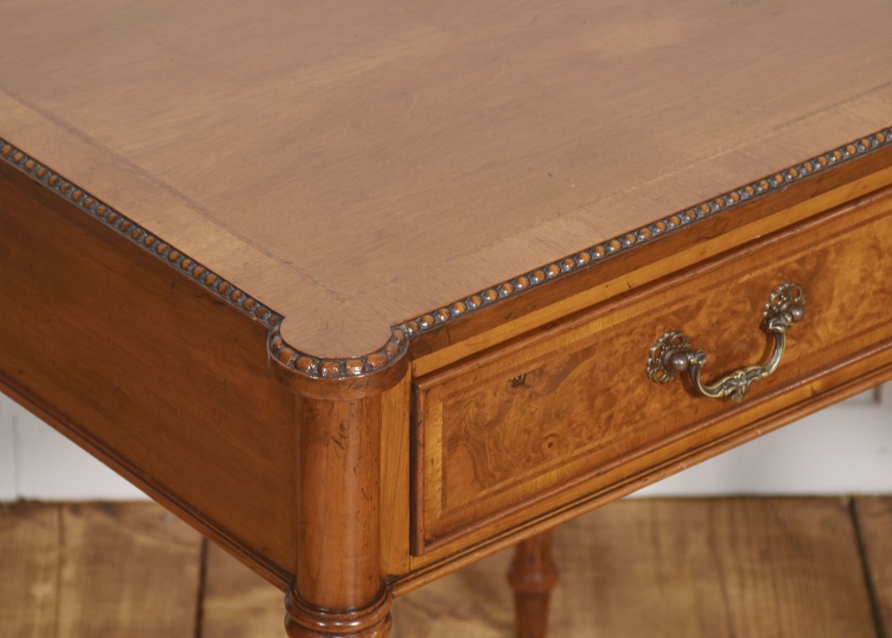 A pair of Edwardian walnut side tables featuring single drawers with brass handles and fluted turned legs. View V