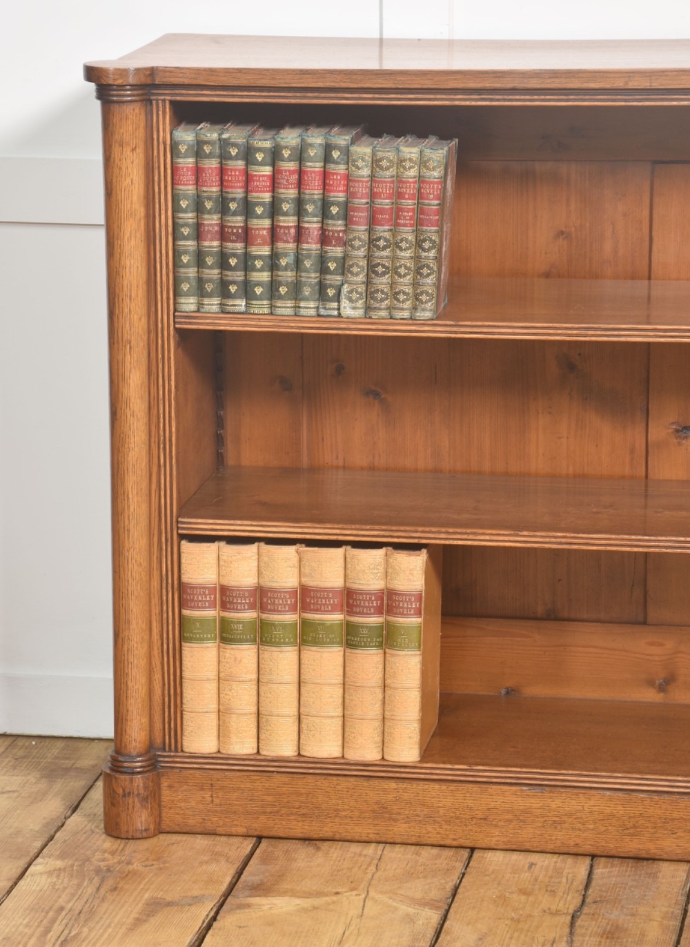 A late nineteenth-century warm brown oak open bookcase featuring three horizontal shelves flanked by fluted side pilasters on a plinth base. View III
