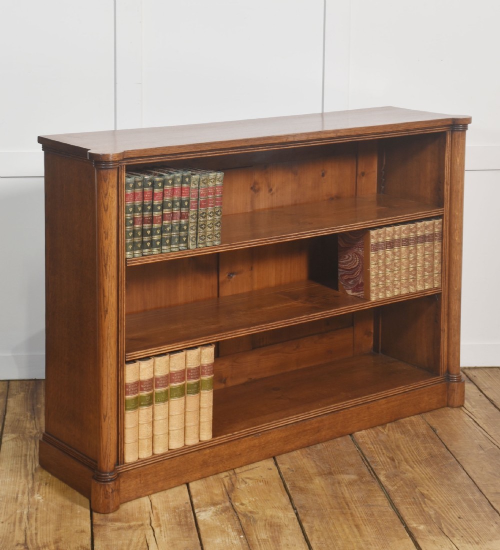 A late nineteenth-century warm brown oak open bookcase featuring three horizontal shelves flanked by fluted side pilasters on a plinth base. View V