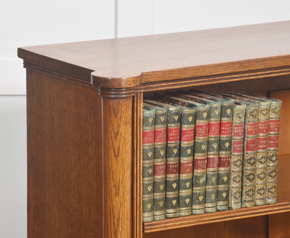 A late nineteenth-century warm brown oak open bookcase featuring three horizontal shelves flanked by fluted side pilasters on a plinth base. View VI