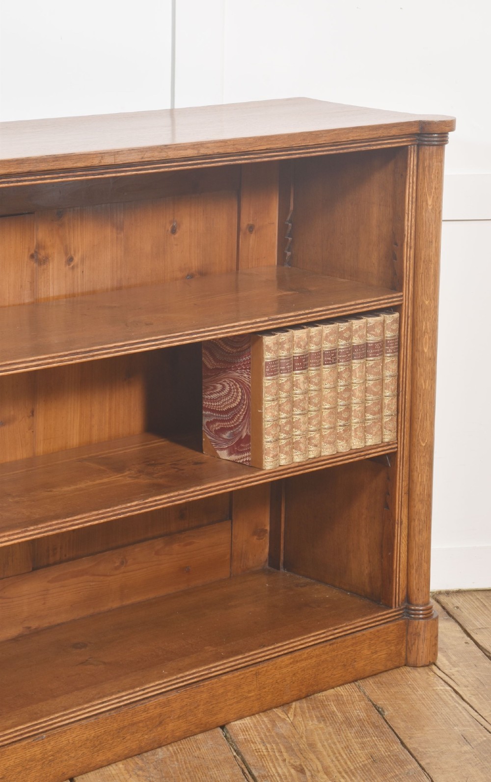 A late nineteenth-century warm brown oak open bookcase featuring three horizontal shelves flanked by fluted side pilasters on a plinth base. View VII