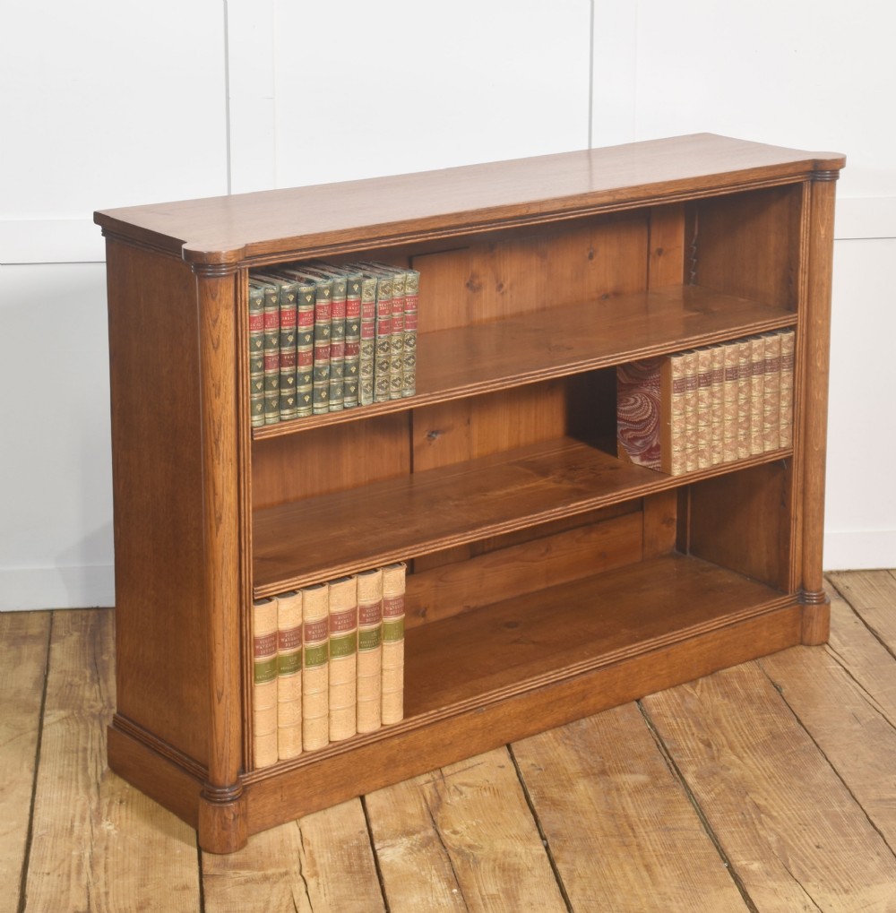 A late nineteenth-century warm brown oak open bookcase featuring three horizontal shelves flanked by fluted side pilasters on a plinth base. View VIII