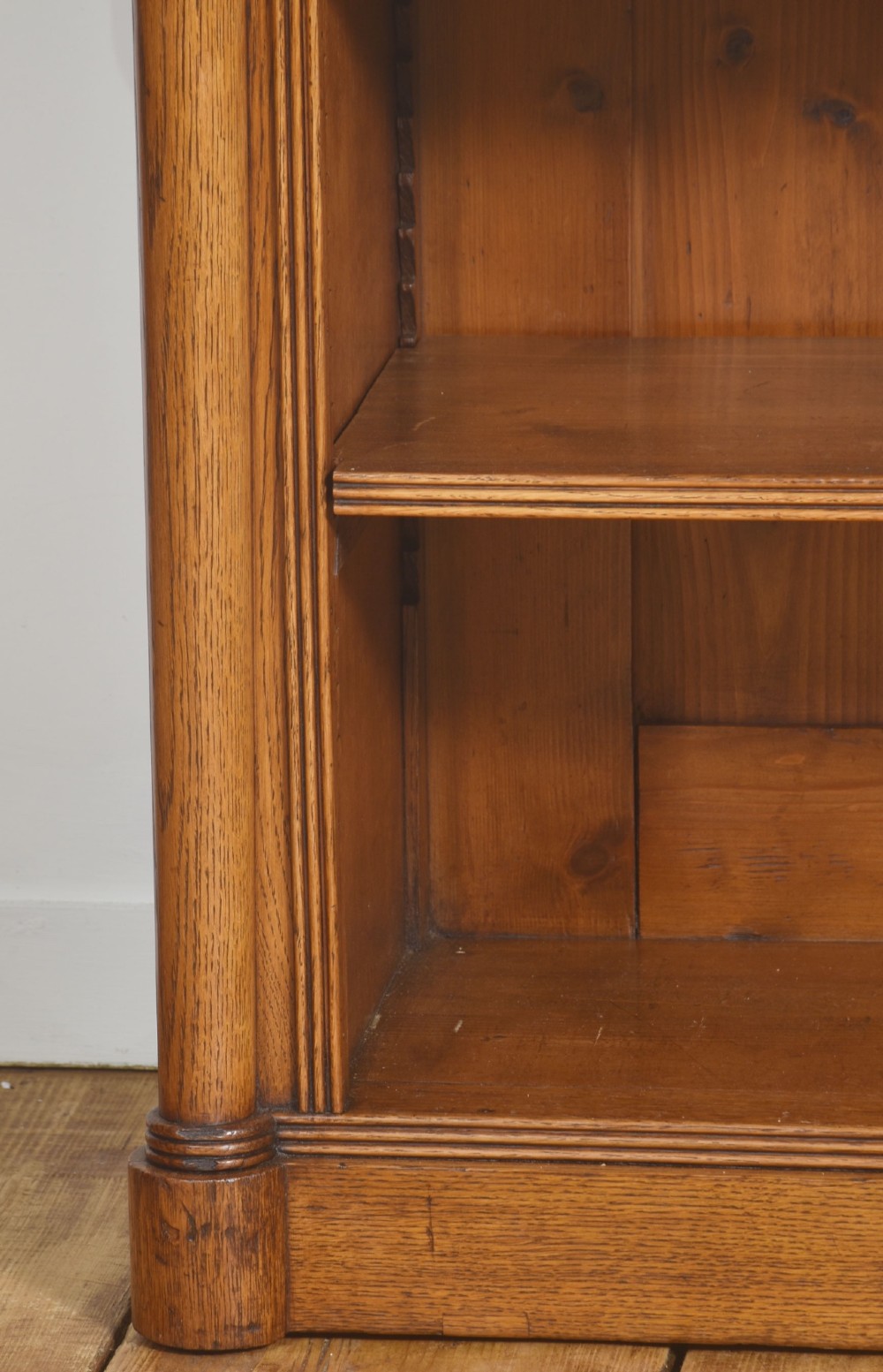 A late nineteenth-century warm brown oak open bookcase featuring three horizontal shelves flanked by fluted side pilasters on a plinth base. View XI