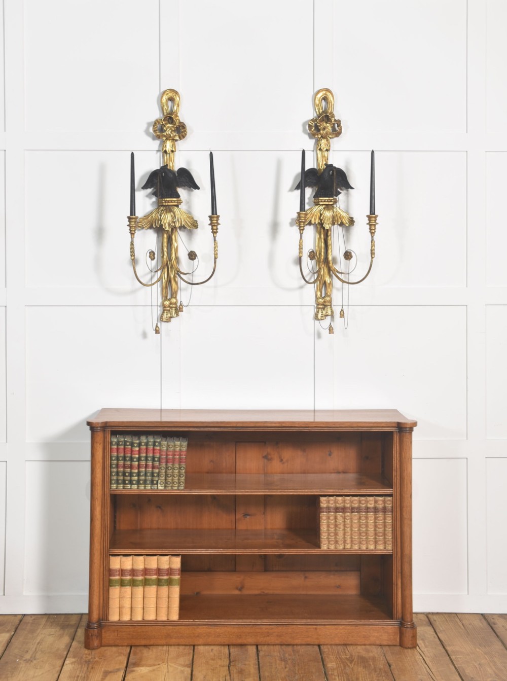 A pair of George III style giltwood wall sconces featuring carved ribbon crestings, dark eagle motifs, and twin candle arms. View III