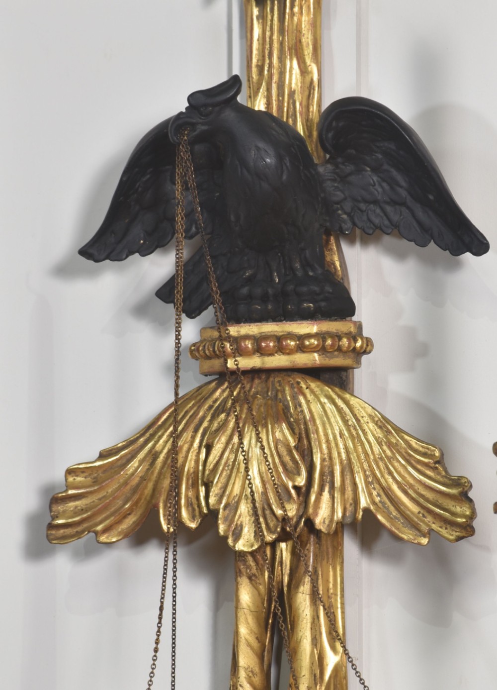 A pair of George III style giltwood wall sconces featuring carved ribbon crestings, dark eagle motifs, and twin candle arms. View VI