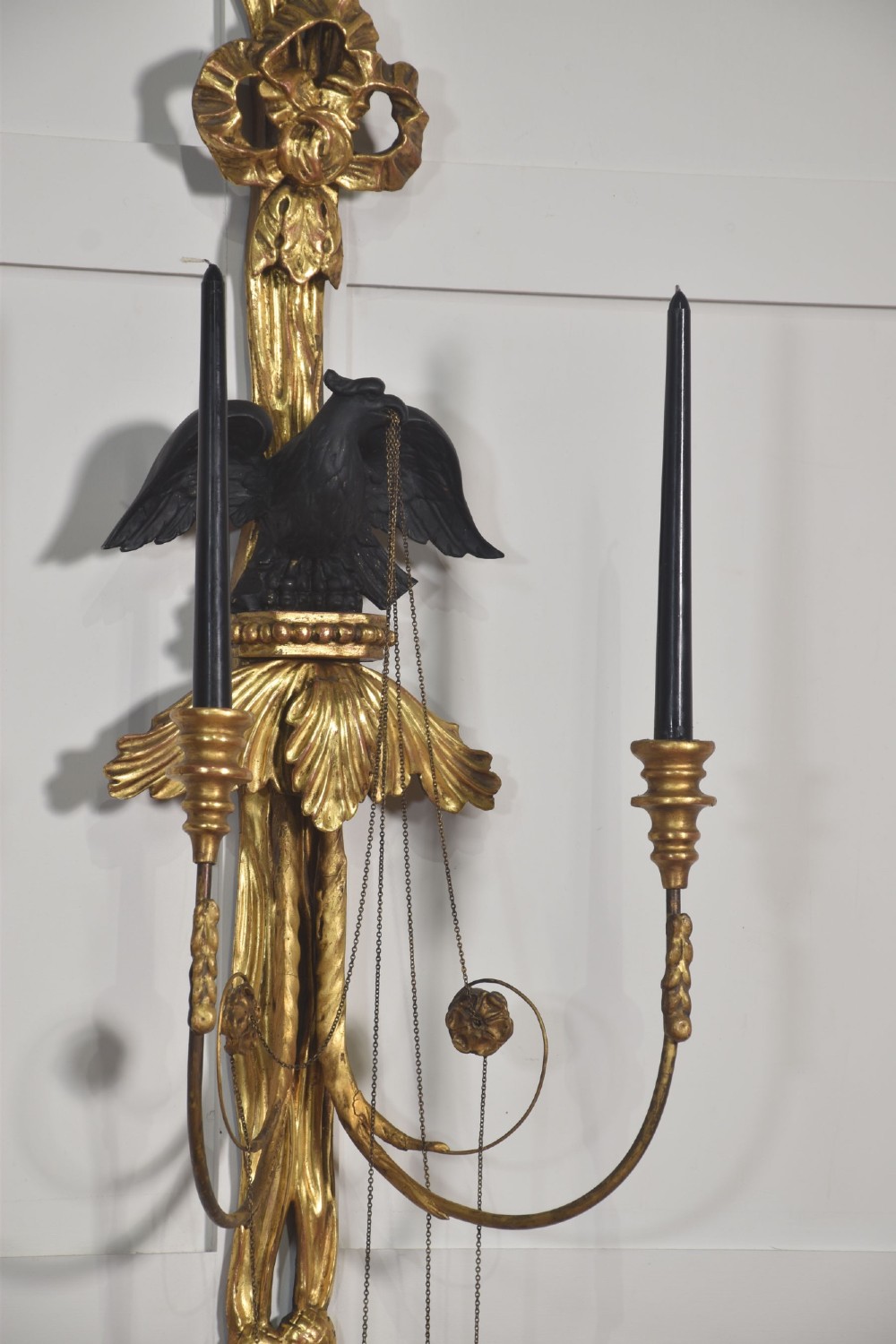 A pair of George III style giltwood wall sconces featuring carved ribbon crestings, dark eagle motifs, and twin candle arms. View VIII