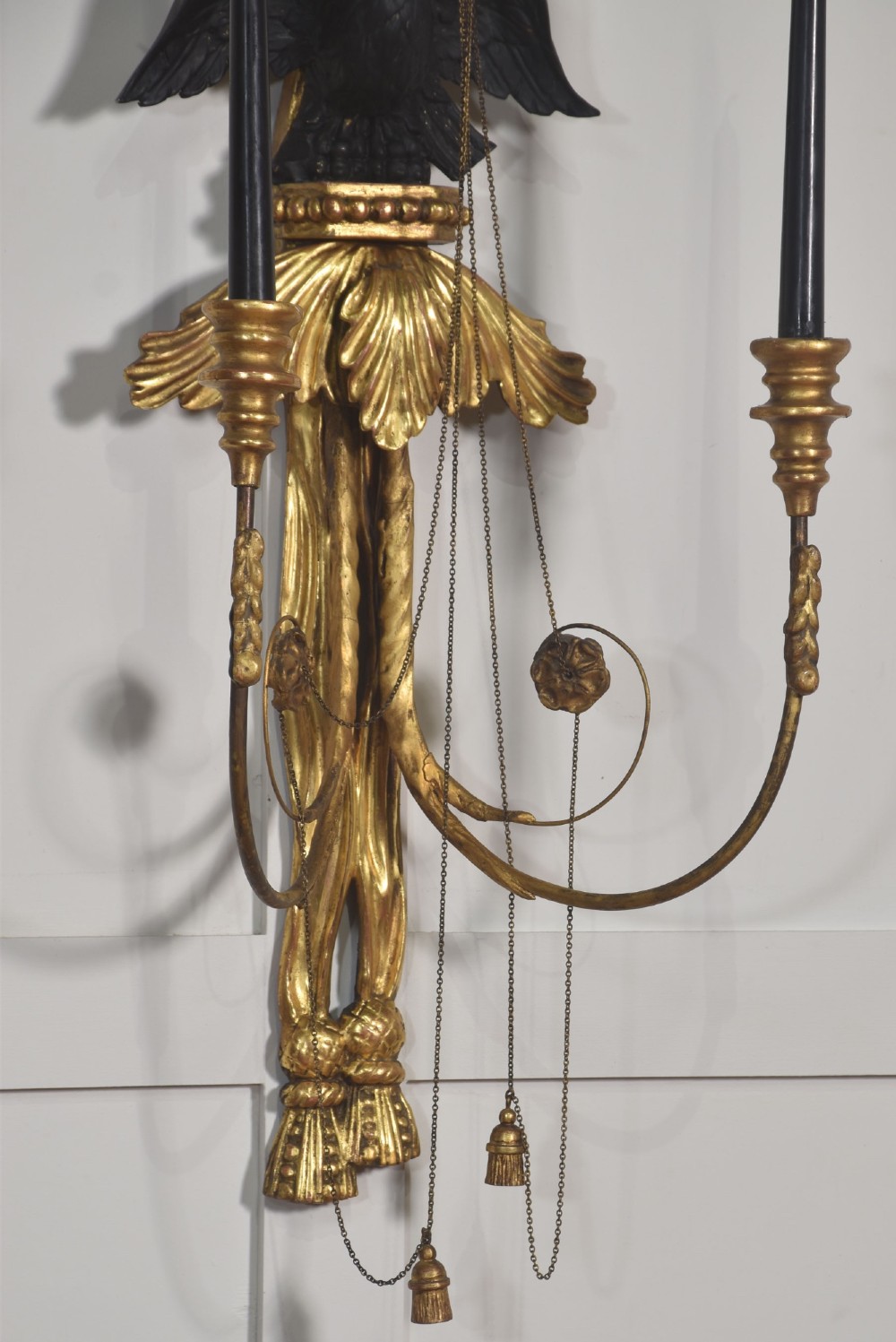 A pair of George III style giltwood wall sconces featuring carved ribbon crestings, dark eagle motifs, and twin candle arms. View IX