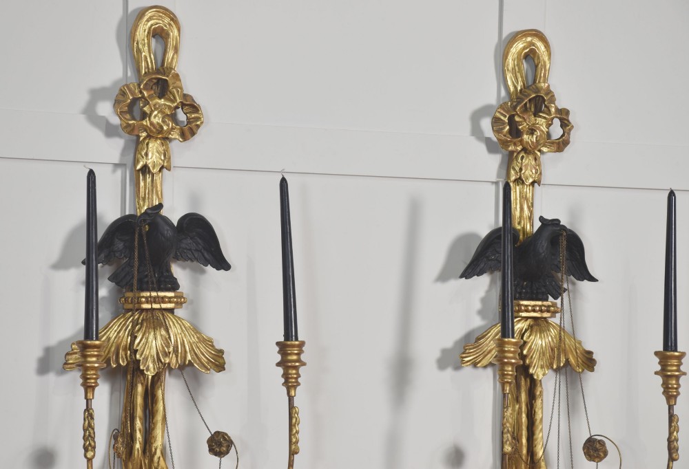 A pair of George III style giltwood wall sconces featuring carved ribbon crestings, dark eagle motifs, and twin candle arms. View XI