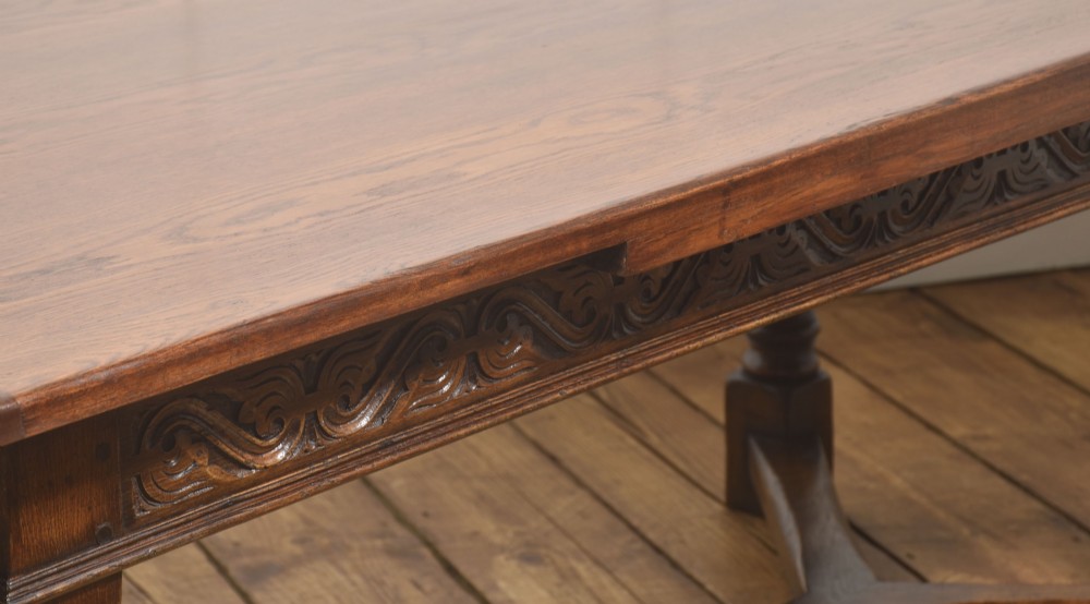 An extended dark oak Jacobean style dining table featuring carved friezes, turned baluster legs, and a sturdy stretcher base. View V