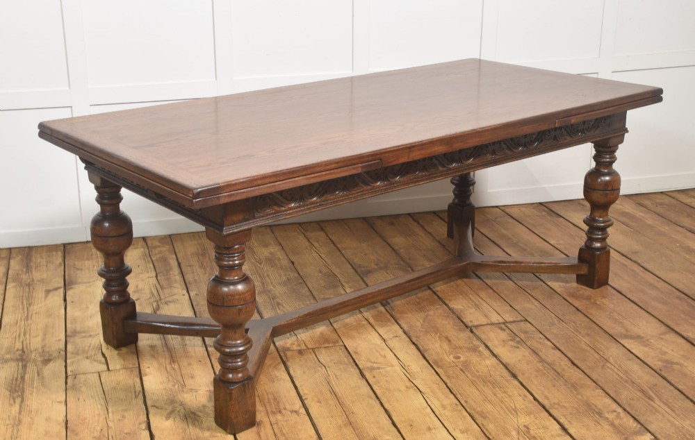 An extended dark oak Jacobean style dining table featuring carved friezes, turned baluster legs, and a sturdy stretcher base. View VI