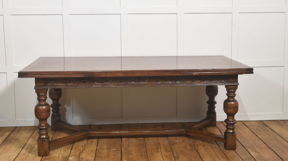 An extended dark oak Jacobean style dining table featuring carved friezes, turned baluster legs, and a sturdy stretcher base. View VII